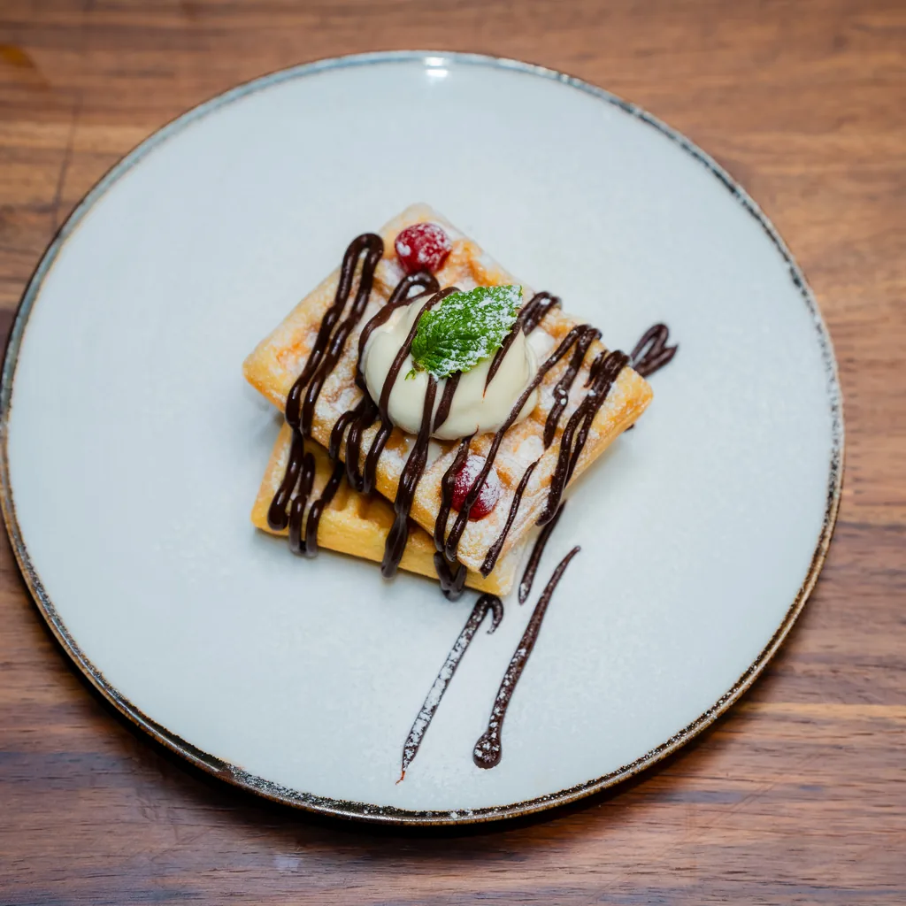 A sweet dessert plate with cream, berries and chocolate drizzle